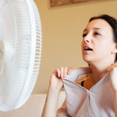 a woman sweats in front of a fan
