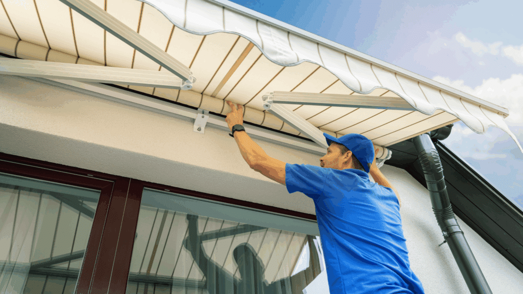 man in blue shirt installing window awning to home