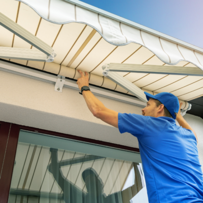 man in blue shirt installing window awning to home